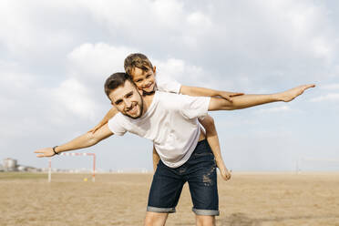 Man carrying boy piggyback on the beach - JRFF03435