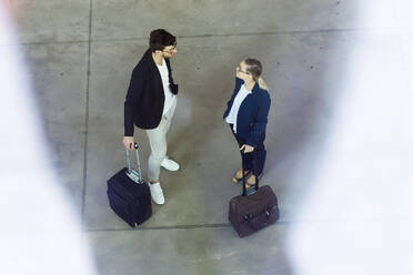 Zwei junge Geschäftspartner mit viel Gepäck im Gespräch - JSRF00375