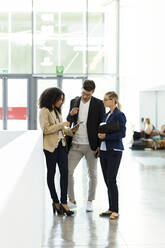 Young business people using a tablet in a foyer - JSRF00385