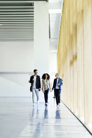 Young business people walking and talking in a hallway stock photo