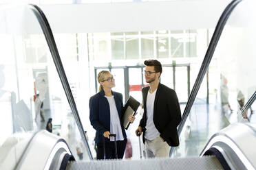 Zwei junge Geschäftspartner unterhalten sich auf einer Rolltreppe - JSRF00398