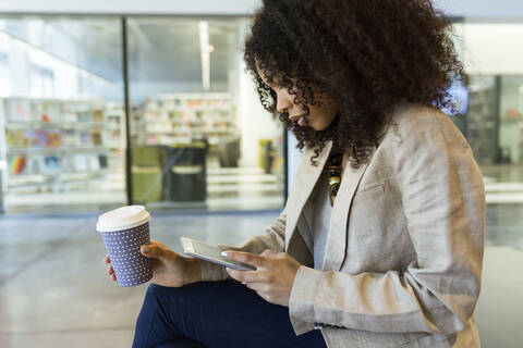 Junge Geschäftsfrau mit Kaffee zum Mitnehmen und Tablet, lizenzfreies Stockfoto