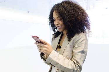 Smiling young businesswoman using a smartphone - JSRF00428