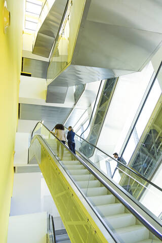 Junge Geschäftsleute auf einer Rolltreppe, lizenzfreies Stockfoto