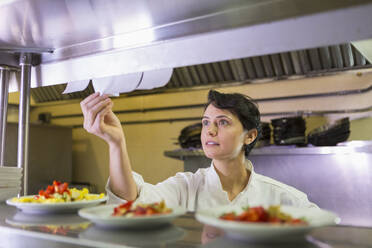 Caucasian chef reading orders in restaurant kitchen - BLEF08235