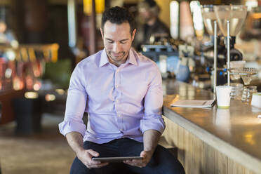 Hispanischer Geschäftsmann benutzt digitales Tablet in einem Café - BLEF08242