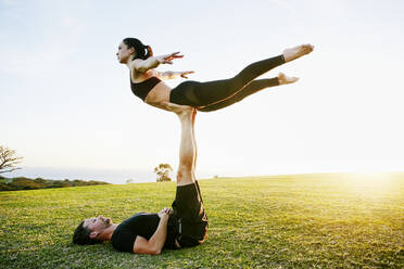 Caucasian couple doing acro yoga in park - BLEF08273