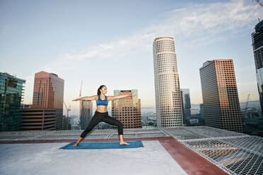 Mixed race woman practicing yoga on urban rooftop - BLEF08276
