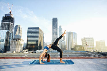 Mixed race woman practicing yoga on urban rooftop - BLEF08278