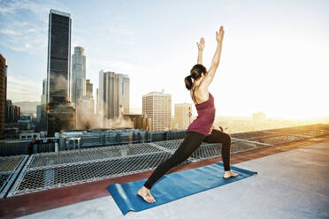 Mixed race woman practicing yoga on urban rooftop - BLEF08281