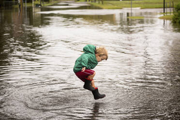 Caucasian boy jumping in puddle - BLEF08296