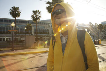 Mixed race woman in hoody and sunglasses walking - BLEF08338