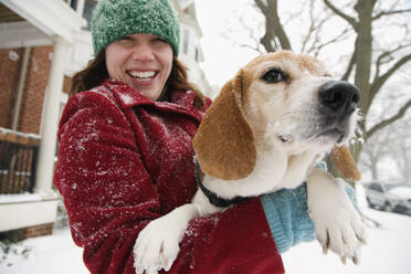 Kaukasische Frau hält Hund im Schnee - BLEF08343