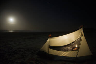 Caucasian man camping on beach - BLEF08372