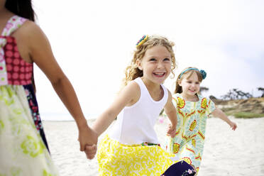 Kinder halten sich an den Händen und laufen am Strand - BLEF08388