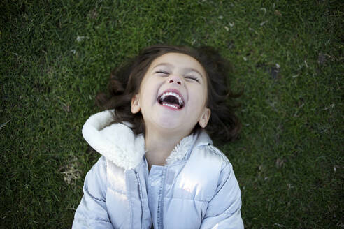 Laughing mixed race girl laying in grass - BLEF08442
