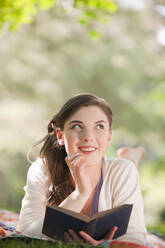 Caucasian woman reading book outdoors - BLEF08467