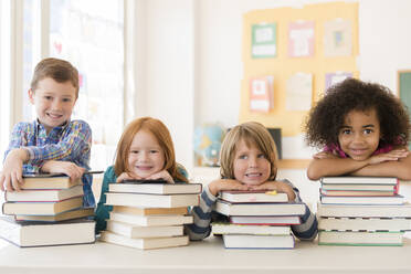Schüler ruhen sich auf Bücherstapeln im Klassenzimmer aus - BLEF08472