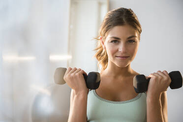 Mixed race woman lifting weights in gym - BLEF08524