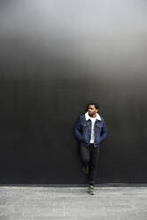 Mann mit Jeansjacke vor einem dunklen Hintergrund - IGGF01266