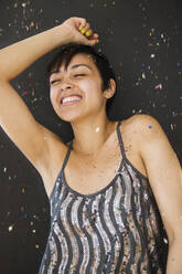 Smiling mixed race woman dancing in confetti - BLEF08550
