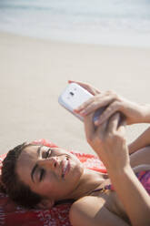 Kaukasische Frau benutzt Mobiltelefon am Strand - BLEF08596
