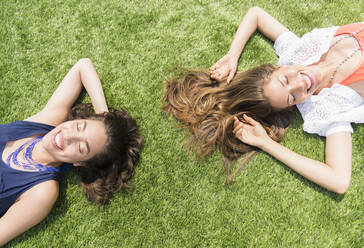 Hispanic women laying in grass outdoors - BLEF08643