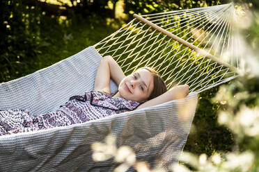 Germany, Bavaria, Landshut, Girl relaxing in hammock in garden - SARF04324