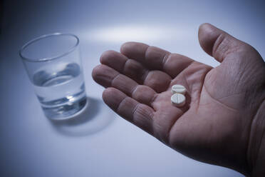 Close up of pills in Hispanic man's hand - BLEF08666