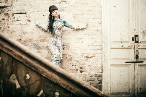 Kaukasische Frau steht auf einer Treppe in einem baufälligen Haus - BLEF08682