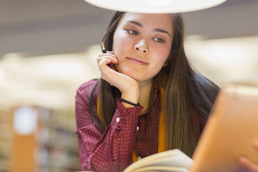 Gemischtrassiger Student liest in der Bibliothek - BLEF08685