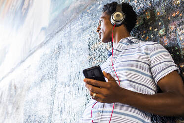 Man listening to cell phone by mural - BLEF08697