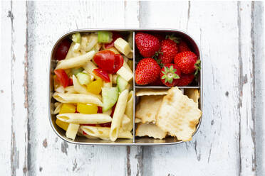 Pasta salad, strawberries and crackers in lunch box on wooden table - LVF08126