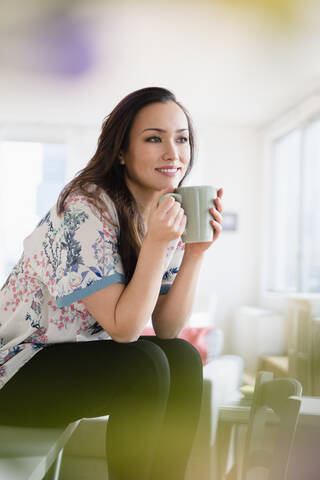 Frau trinkt eine Tasse Kaffee im Wohnzimmer, lizenzfreies Stockfoto