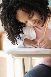 African American student writing in classroom - BLEF08729