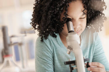 Ein afroamerikanisches Mädchen benutzt ein Mikroskop im naturwissenschaftlichen Unterricht - BLEF08738
