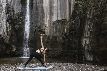 Frau übt Yoga am Wasserfall, Dreieckspose - LJF00363