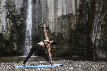 Frau übt Yoga am Wasserfall, Dreieckspose - LJF00364