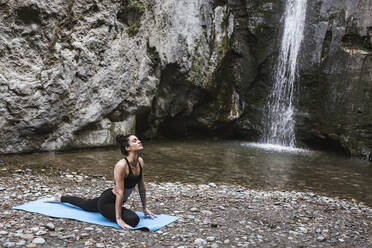 Frau übt Yoga am Wasserfall, Kobra-Pose - LJF00366