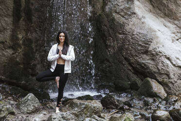 Frau übt Yoga am Wasserfall, Baumstellung - LJF00376