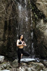 Frau übt Yoga am Wasserfall, Baumstellung - LJF00377