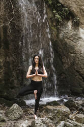 Frau übt Yoga am Wasserfall, Baumstellung - LJF00378