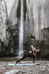 Frau übt Yoga am Wasserfall, Dreieckspose - LJF00381