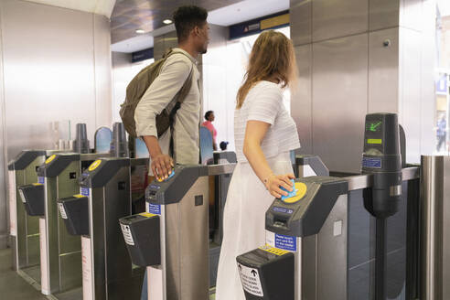 Junges Paar beim Passieren eines U-Bahn-Schalters mit elektronischen Fahrkarten - FBAF00856