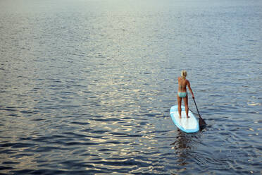 Caucasian woman on paddleboard on lake - BLEF08799