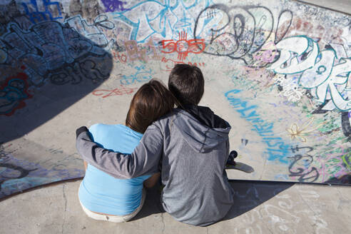 Junge und Mädchen umarmen sich im Skateboardpark - BLEF08805