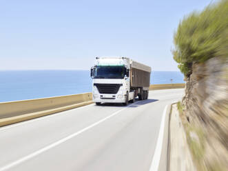 Lkw fährt entlang der Jersey-Barriere der Küstenautobahn, Sitges, Barcelona, Spanien - CVF01242