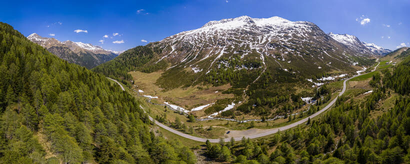 Panoramablick auf eine kurvenreiche Straße durch die bewaldete Landschaft des Defereggentals, Osttirol, Österreich - STSF02082