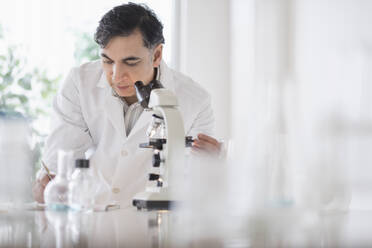 Mixed race scientist using microscope in laboratory - BLEF08849