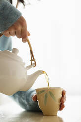 Hispanische Frau gießt eine Tasse Tee ein - BLEF08851